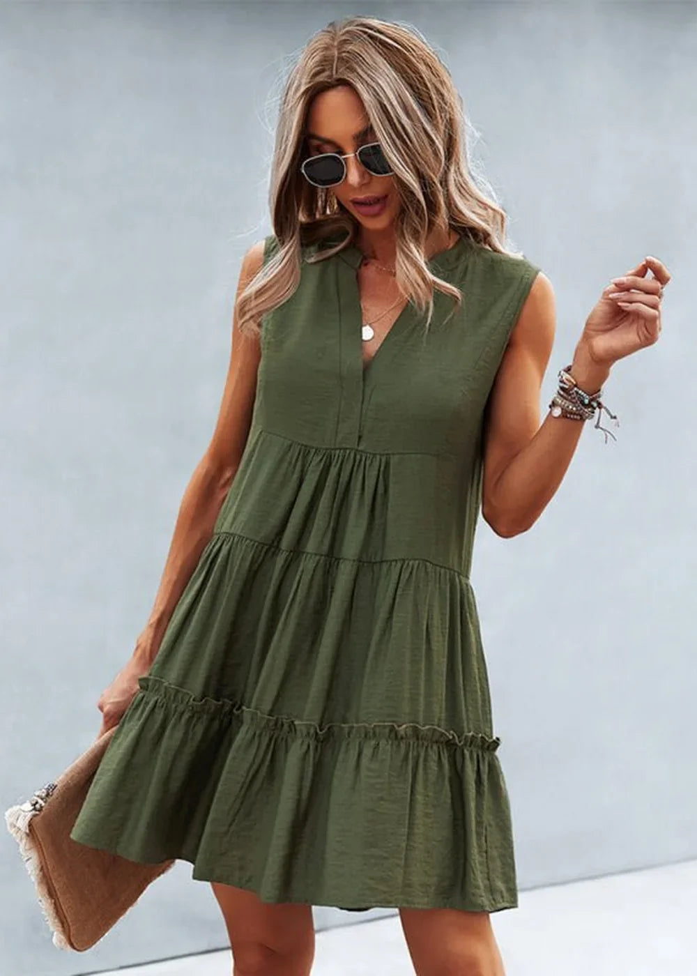 Olive green tiered mini dress with V-neck and ruffled hem on a model.