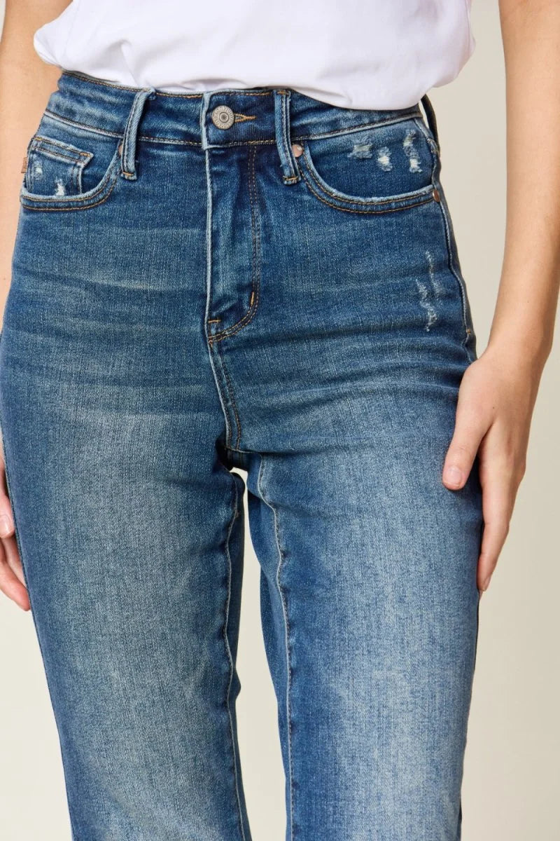 Close-up of distressed medium wash denim jeans with a button fly and whiskering.