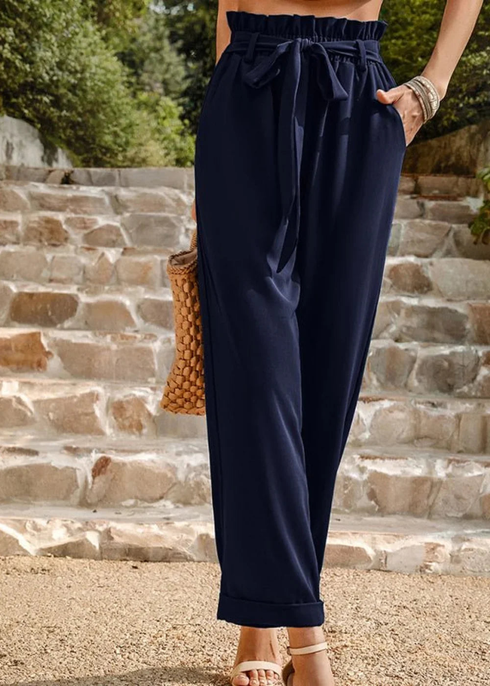Navy blue paperbag waist pants with a tie belt, cuffed hem, and side pockets.