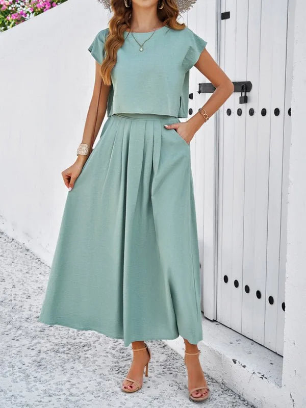 Light green two-piece set with a crop top and pleated midi skirt, on a model.