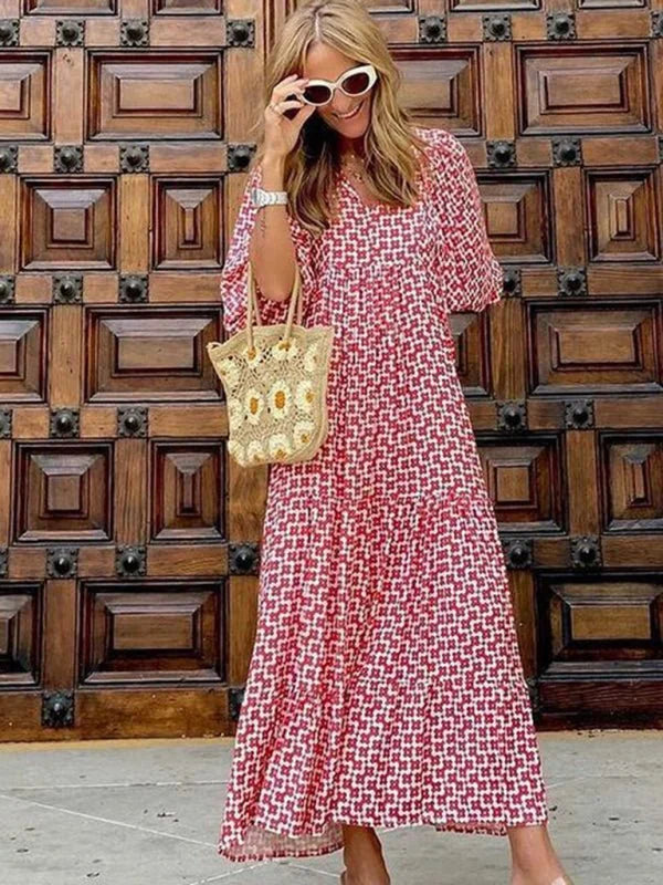 Woman in a red and white geometric print maxi dress, white sunglasses, and a straw bag.