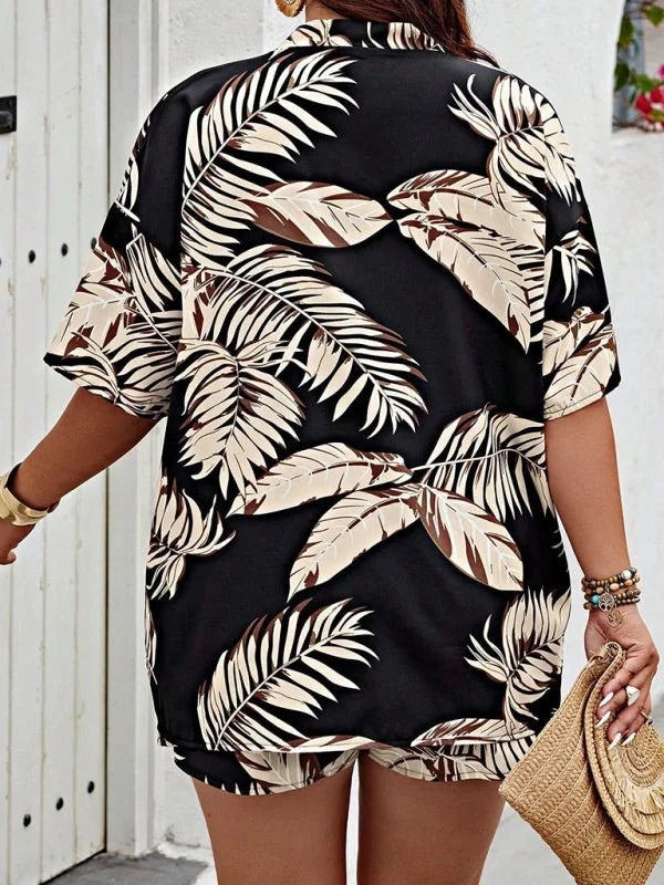 Black tropical leaf print short suit with gold bracelet and straw clutch.