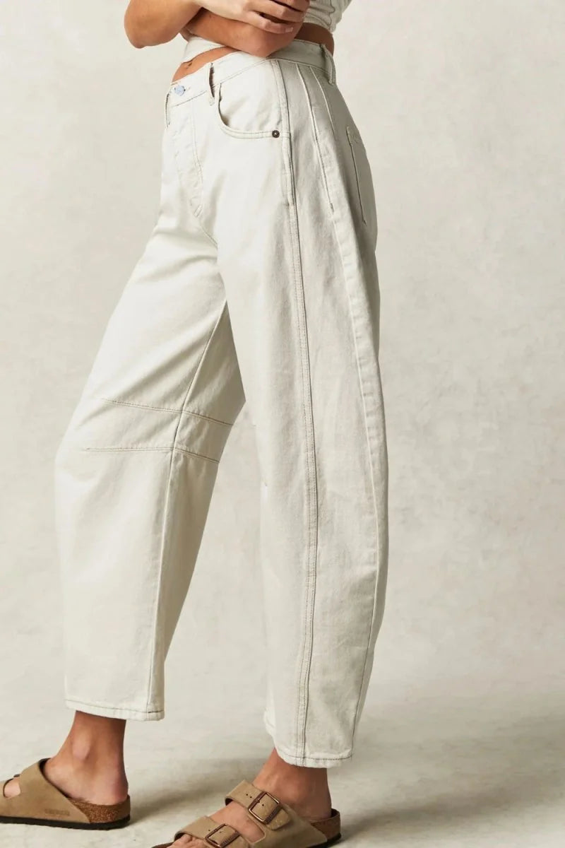 Relaxed fit cream denim pants with visible stitching and panel details, shown on model.