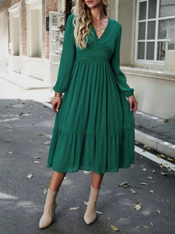 Emerald green midi dress with a tiered hem, v-neckline, and long sleeves, worn with tan ankle boots.