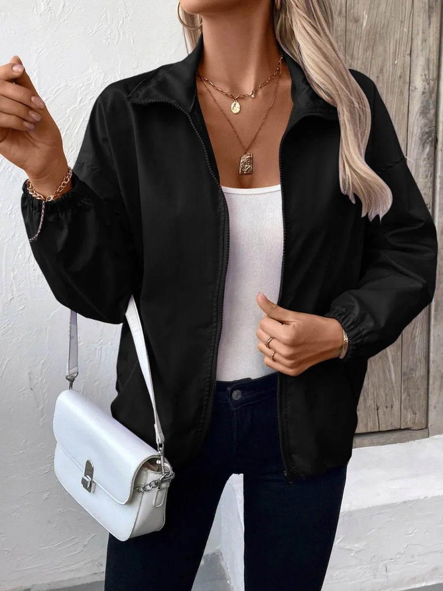 Black bomber jacket with gold-tone chain bracelet and layered necklaces on model