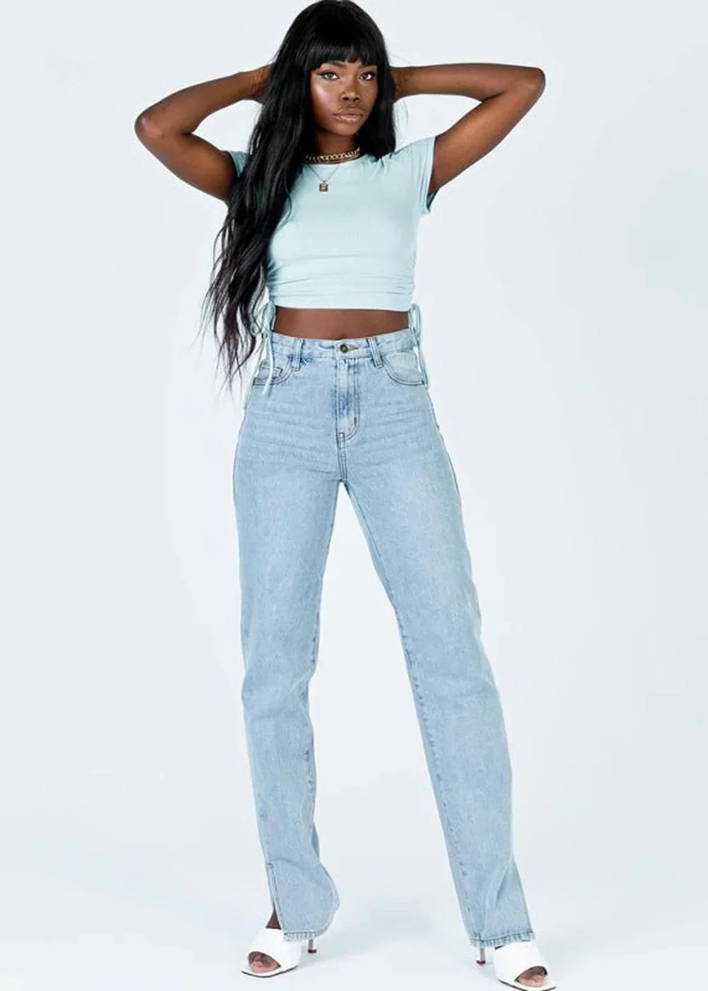 Light blue cropped t-shirt with ruched sides and light wash high-waisted jeans with split hems on a model.