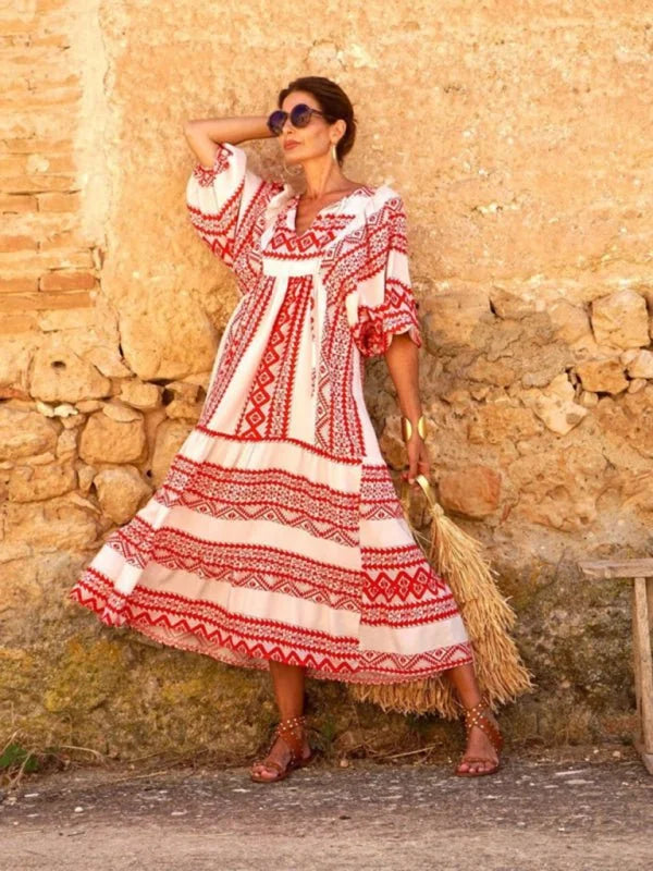 Woman in a flowing white and red geometric print maxi dress with sandals and sunglasses.