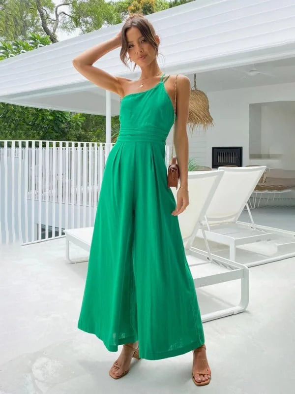 Emerald green one-shoulder wide-leg jumpsuit with a cinched waist, on a model outdoors.