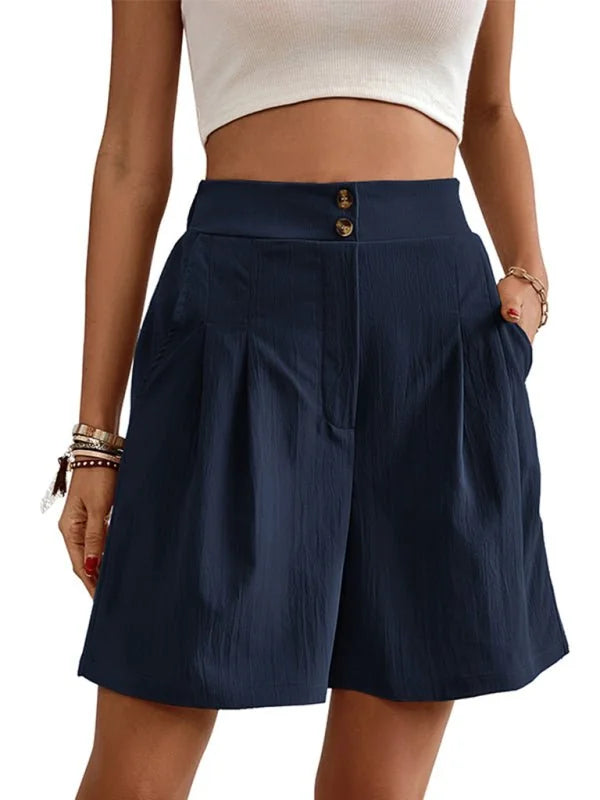Navy blue pleated shorts with a high waist and button closure, shown on a model.