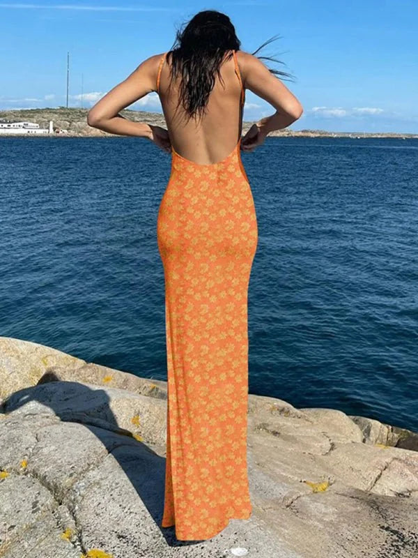 Orange maxi dress with a yellow floral print, featuring a low back and spaghetti straps.