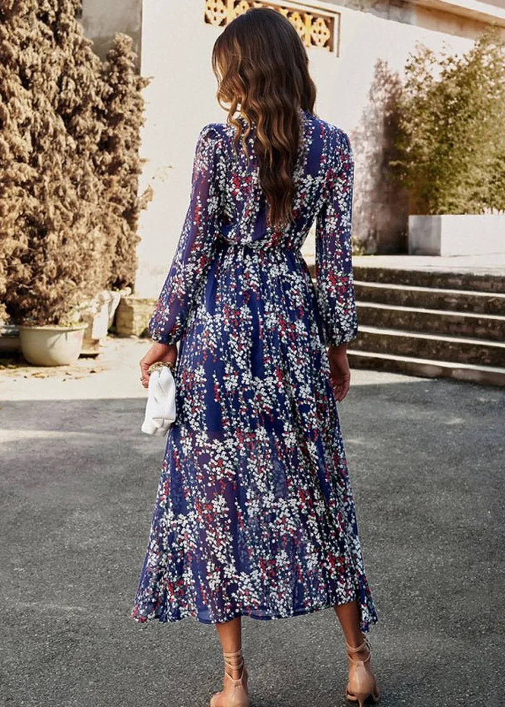 Navy blue chiffon maxi dress with a red and white floral print, long sleeves, and a white clutch.