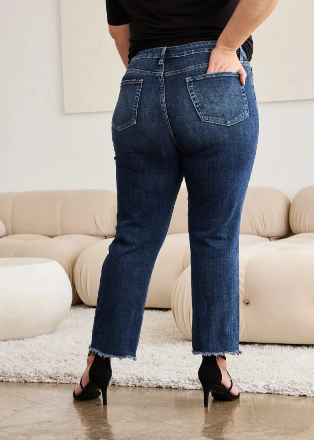 Dark wash denim jeans with frayed hem, regular fit, on model.