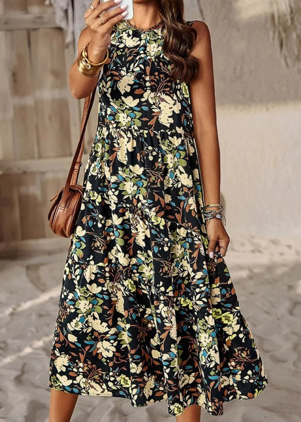 Black floral print midi dress with a tiered skirt, featuring a brown crossbody bag and gold bracelets.