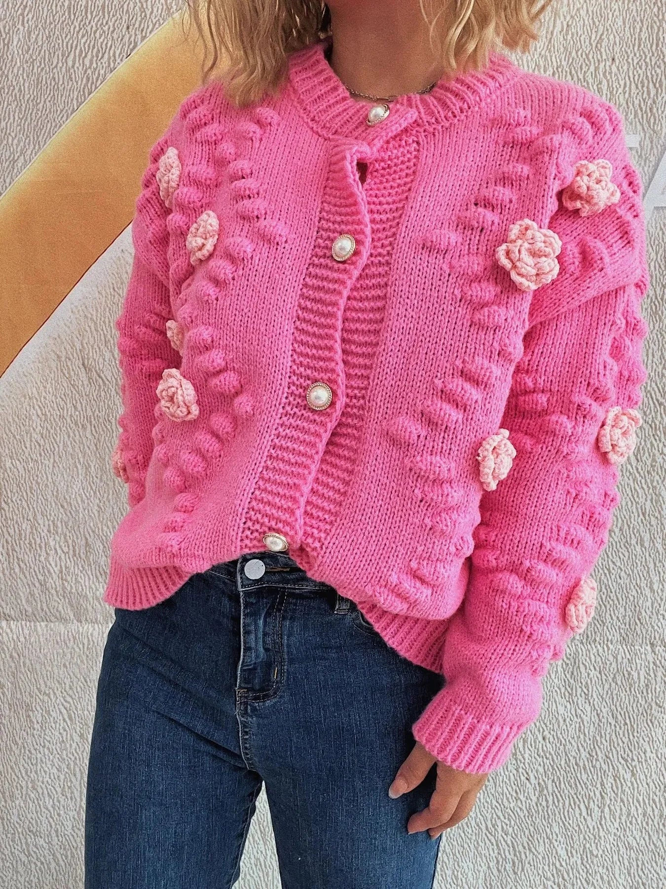 Hot pink knit cardigan with floral appliques, pearl buttons, and textured pattern.