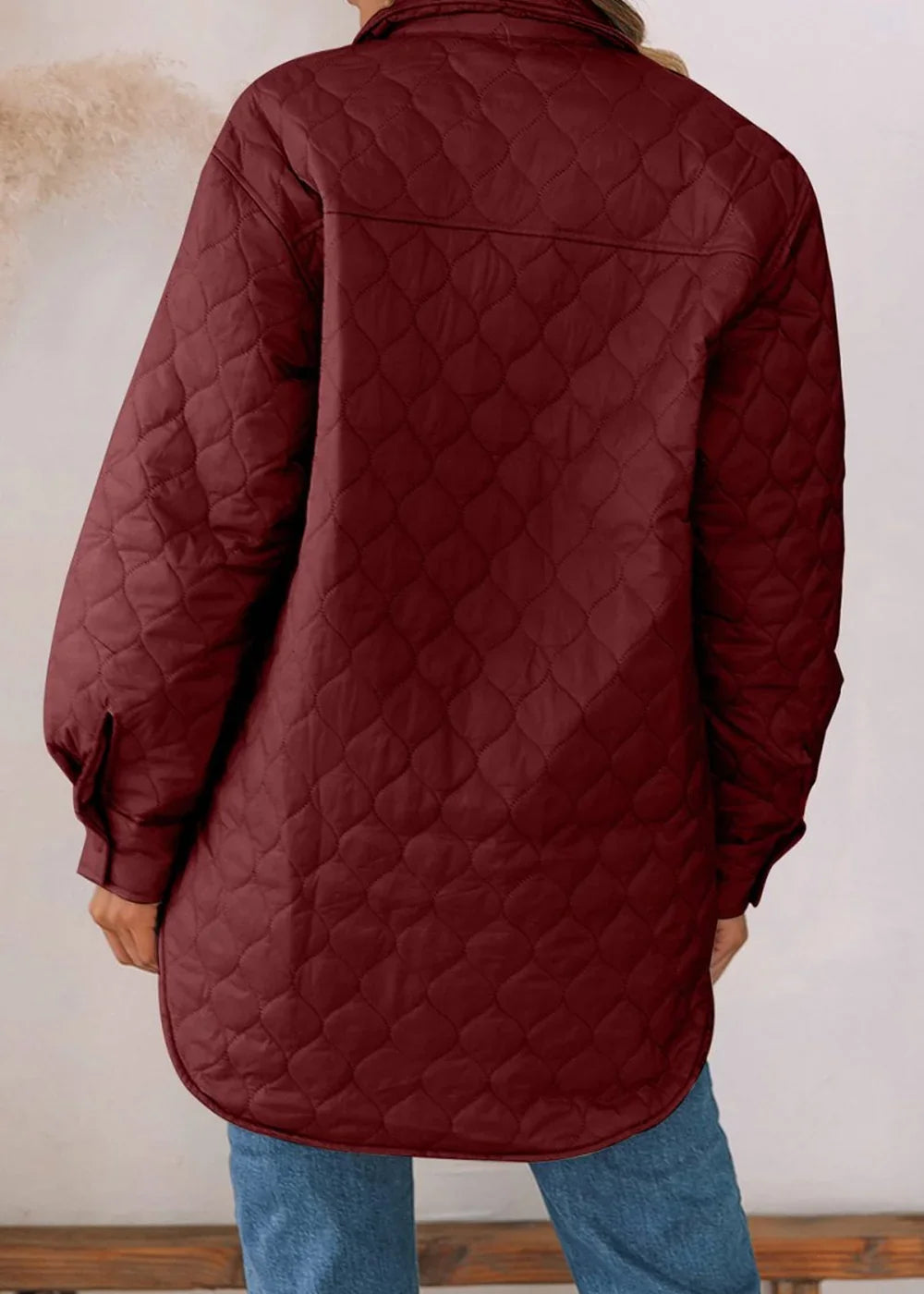 Back view of a maroon quilted jacket with a diamond pattern.