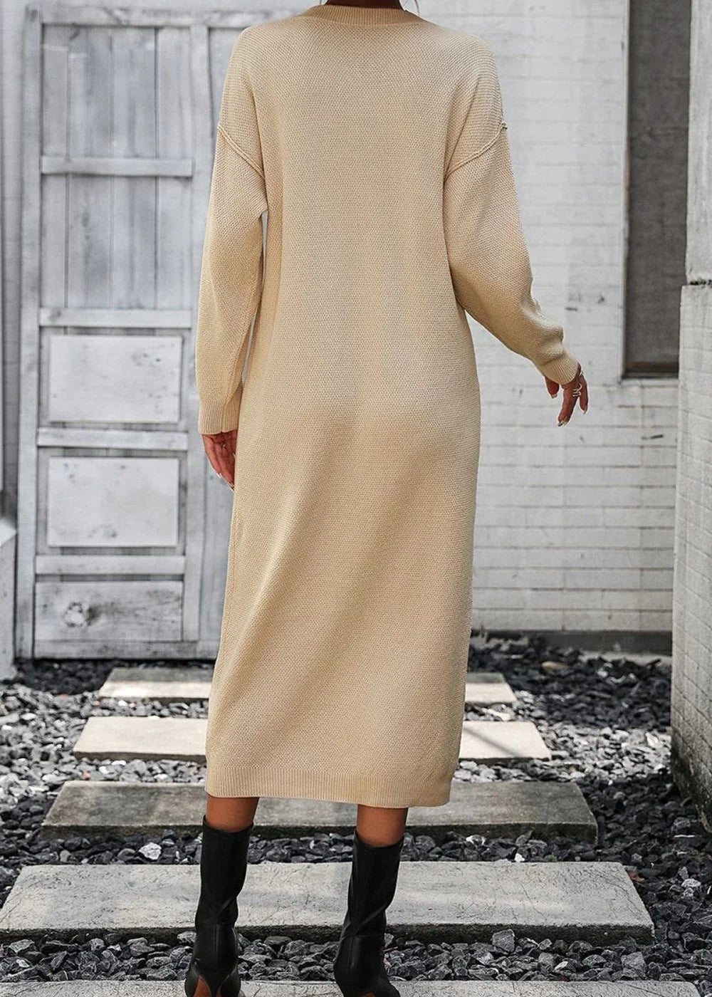 Beige knit sweater dress with long sleeves, shown from the back, paired with black boots.