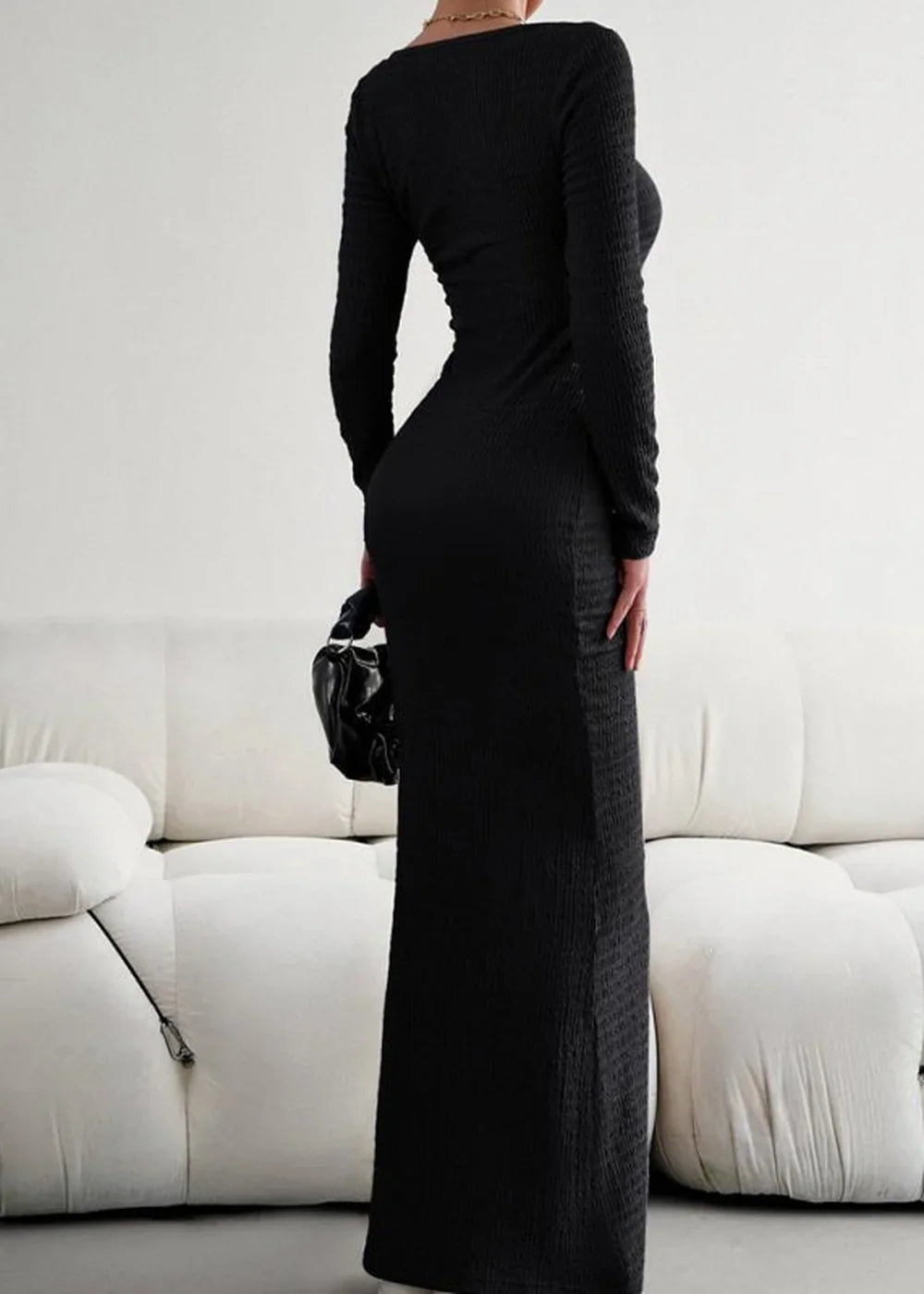 Black ribbed long-sleeve maxi dress with ruched detail, shown on model from the side.