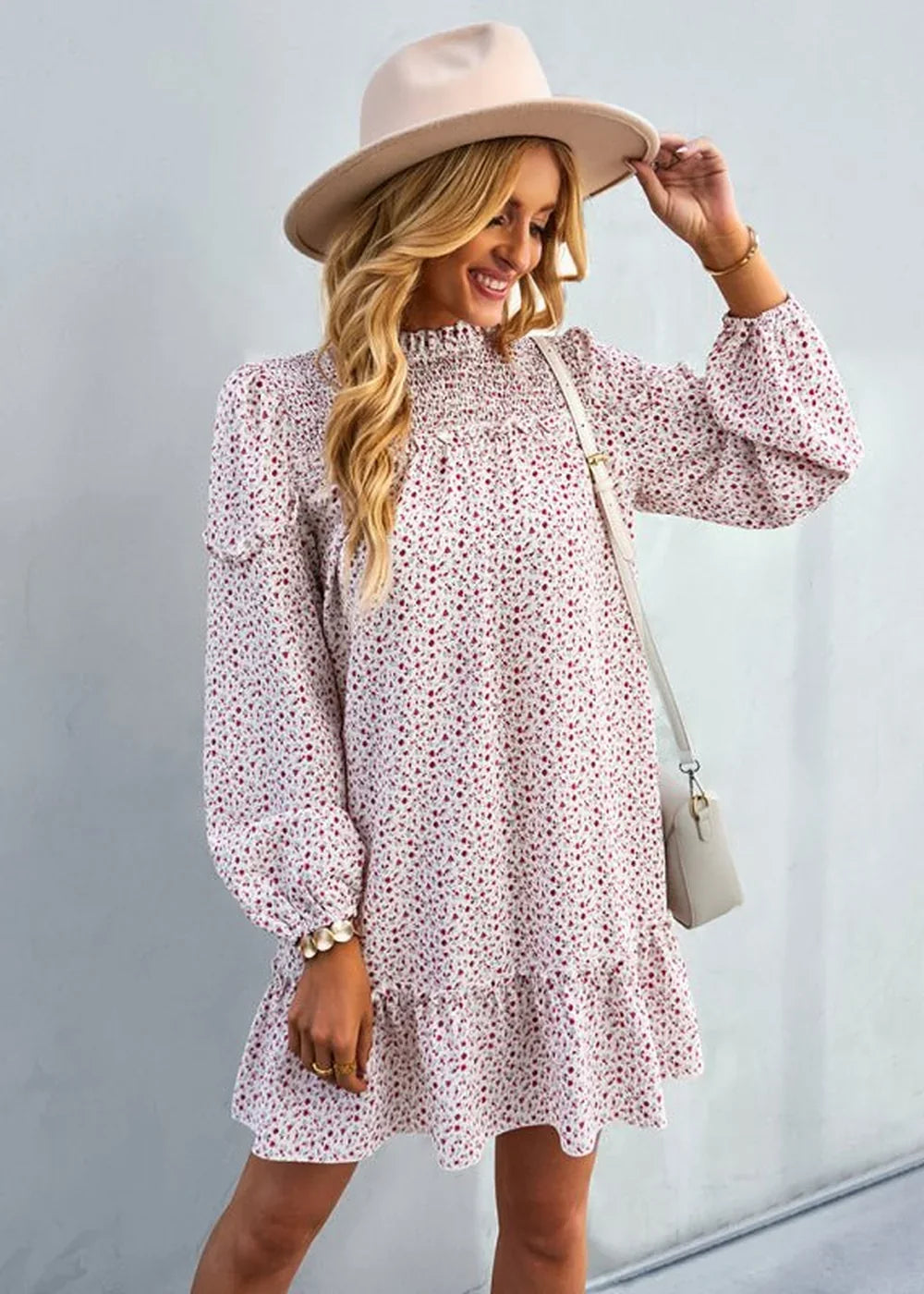 Woman in a white floral print dress with smocked neckline and ruffled hem, wearing a wide-brim hat.