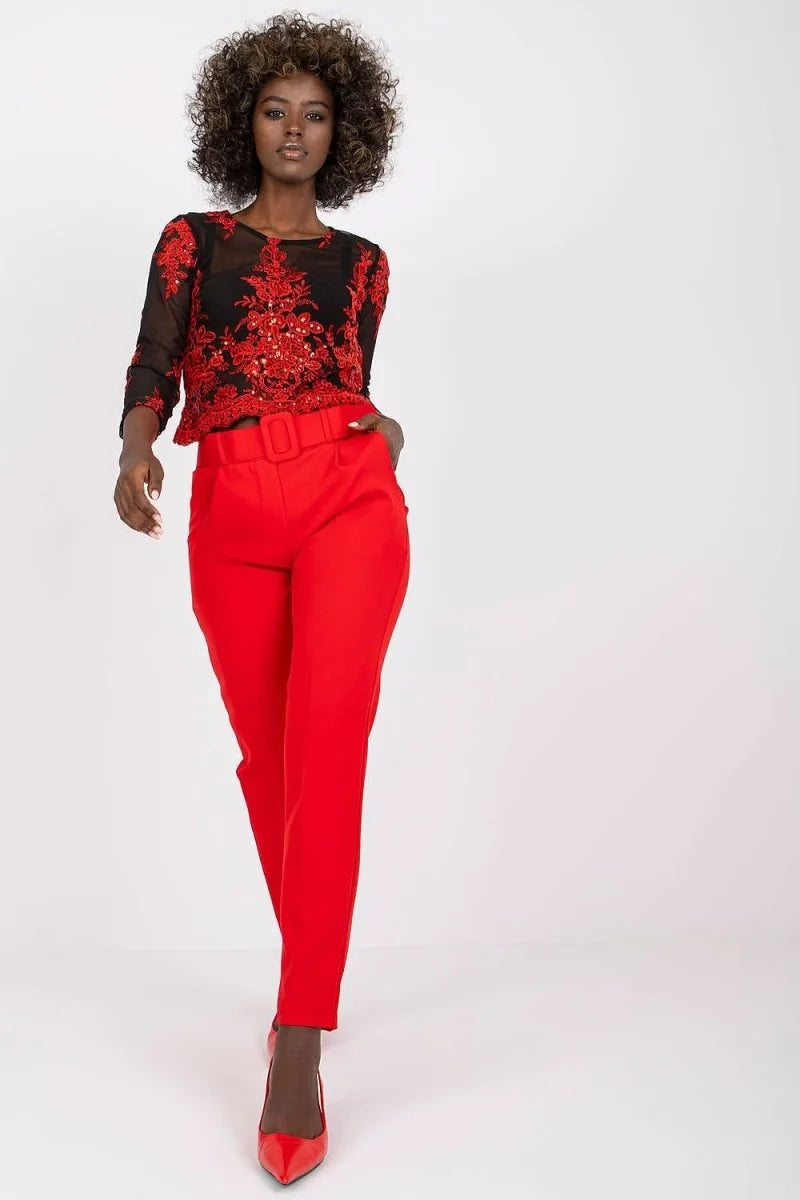 Red high-waisted pants with a belted waist and pockets, worn by a model.