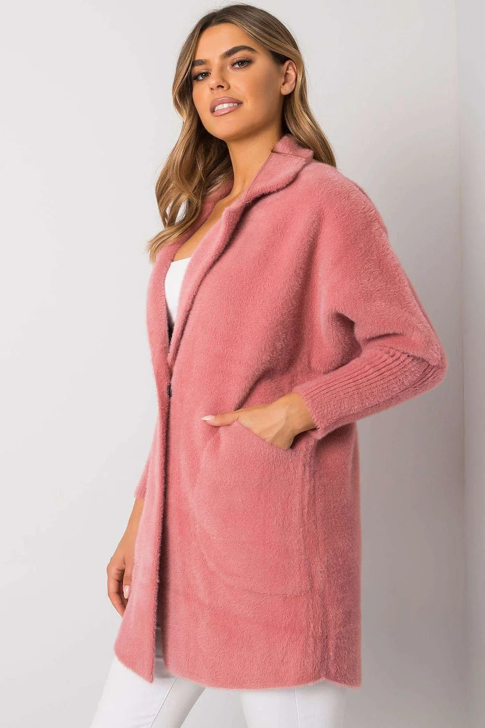 Pink fuzzy cardigan with pockets and ribbed cuffs, on a model.