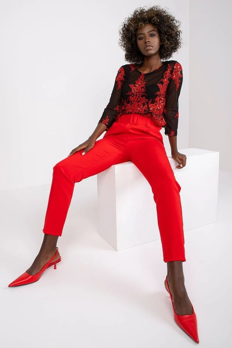 Red high-waisted pants with a belt and a fitted silhouette, worn by a model.