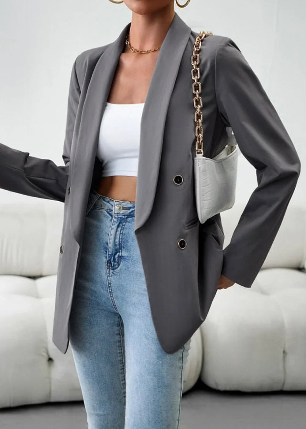 Model in a grey double-breasted blazer, white crop top, and light wash jeans.