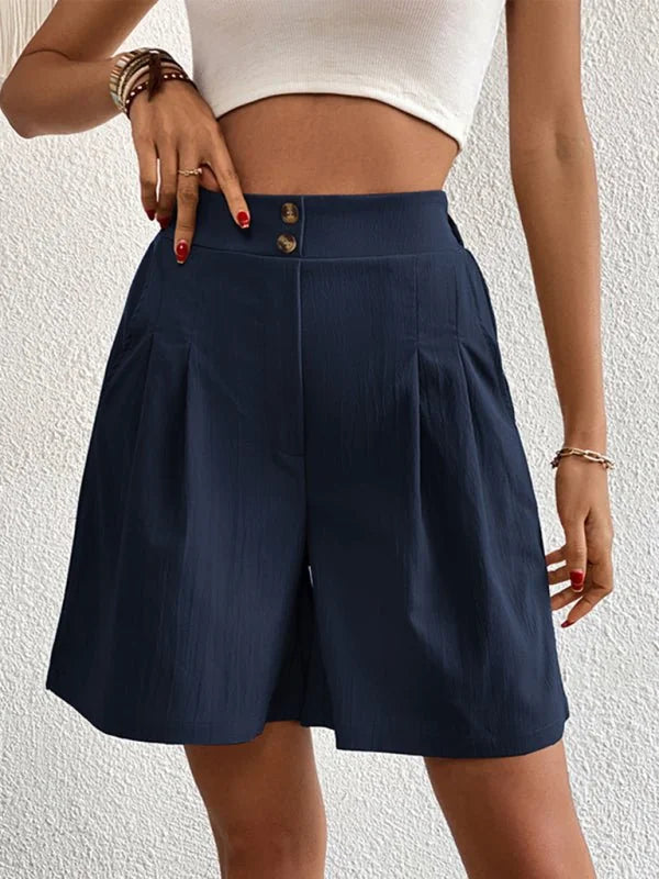 Navy blue pleated shorts with a high waist and textured fabric, shown on a model.