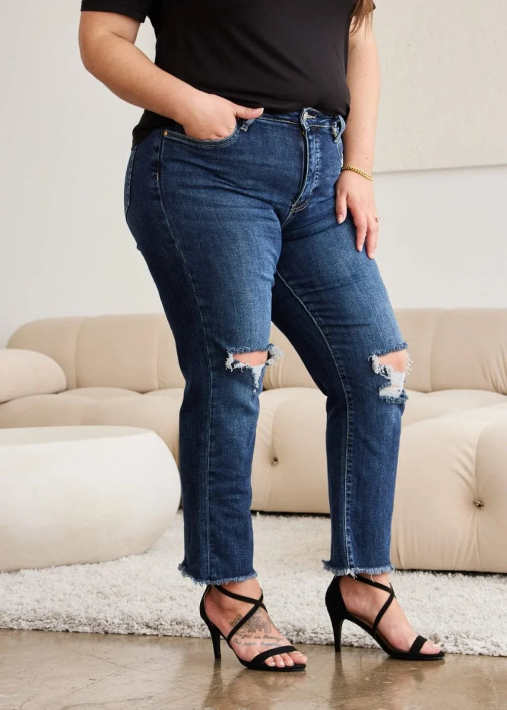 Dark wash distressed denim jeans with frayed hem and a raw edge cuff.