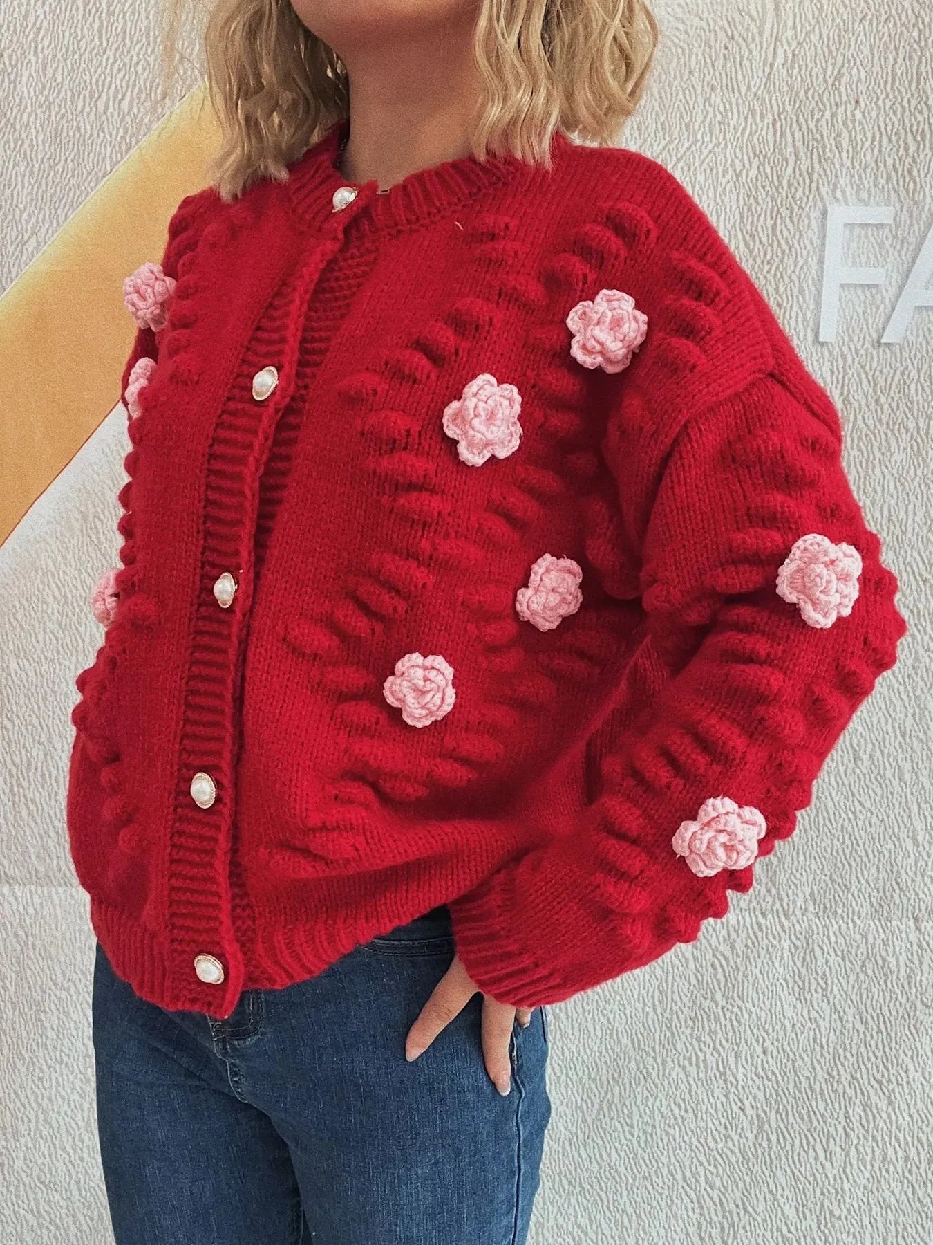 Red knit cardigan with pink floral appliques and pearl buttons.