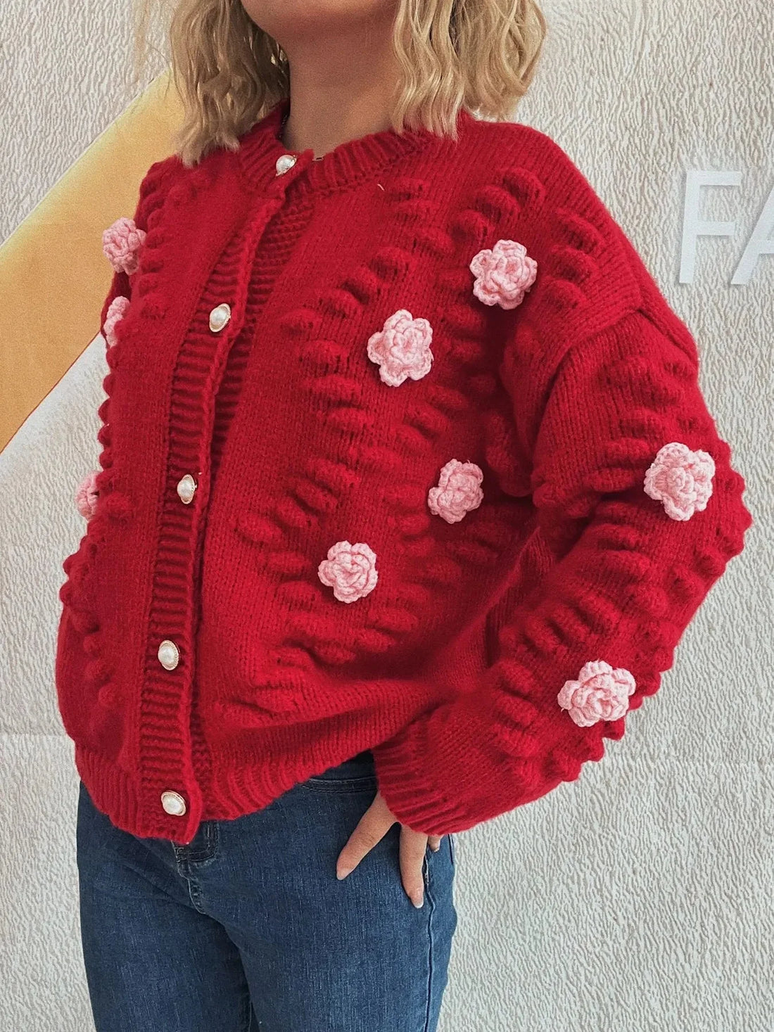 Red knit cardigan with pink floral appliques and pearl buttons.