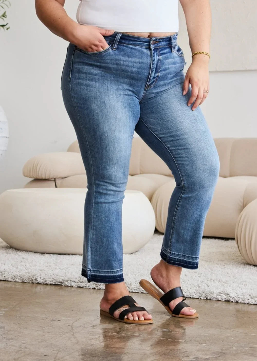 Light wash distressed denim jeans with a cropped flare hem and frayed edges.