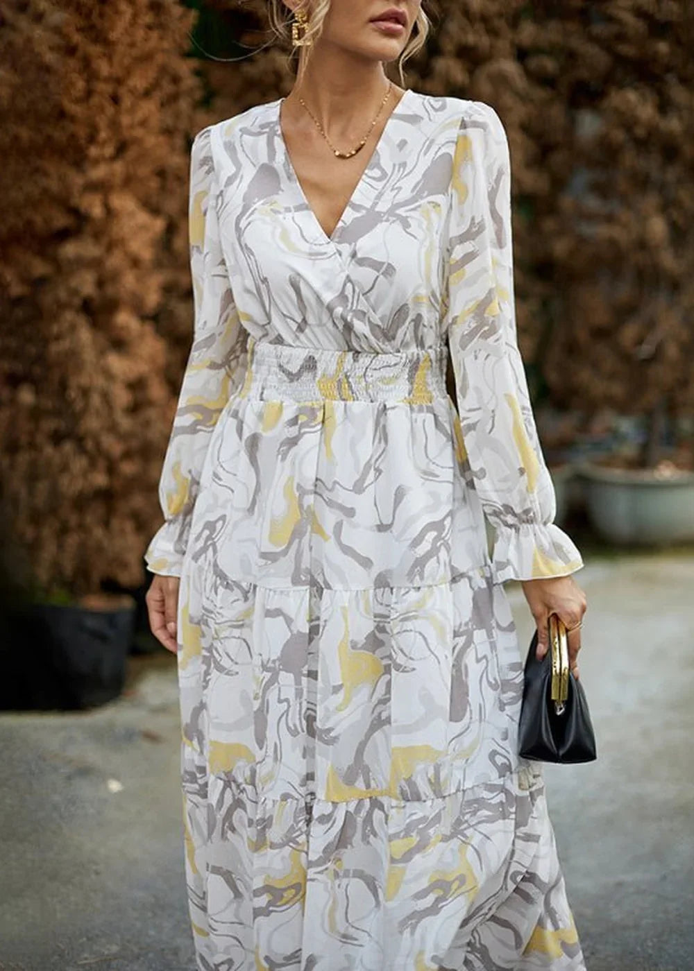 White and yellow abstract print dress with a v-neck, smocked waist, and tiered skirt.