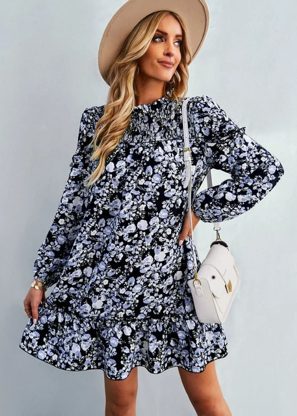 Woman in black and blue floral print dress with smocked bodice and white crossbody bag.
