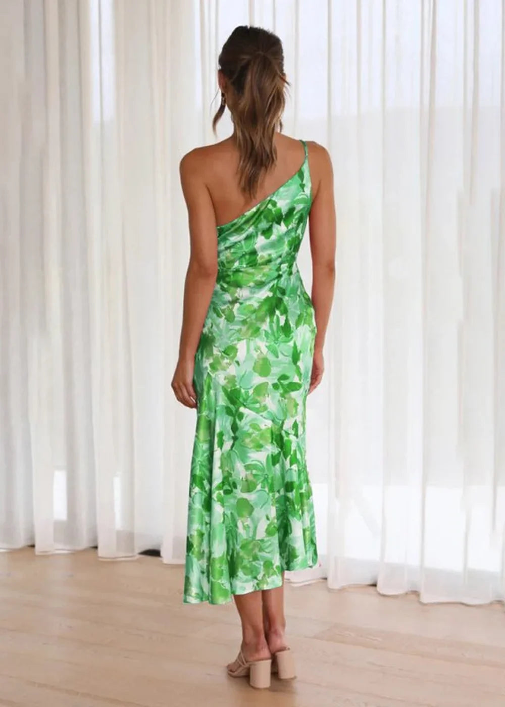 Woman from behind wearing a green floral print one-shoulder midi dress.