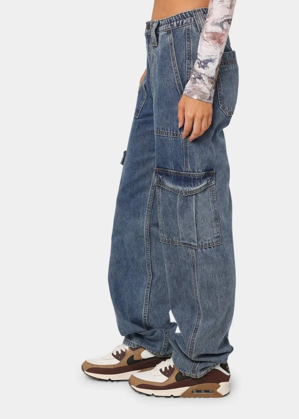 Medium wash denim cargo pants with large side pockets and a relaxed fit.