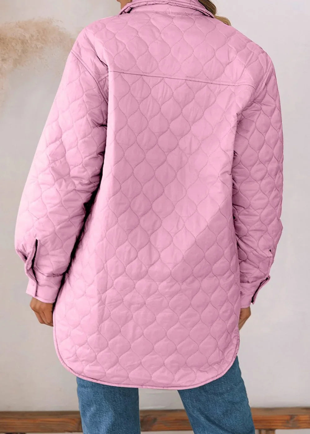 Back view of a pink quilted jacket with a collar and button cuffs, styled with blue jeans.