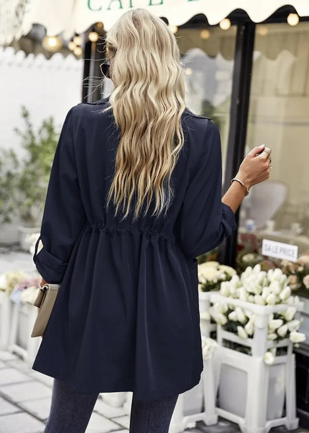 Navy blue cinched-waist trench coat with long sleeves, shown from the back.