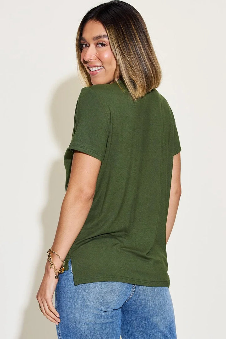 Green short-sleeve t-shirt with side slit, paired with blue jeans and a gold charm bracelet.