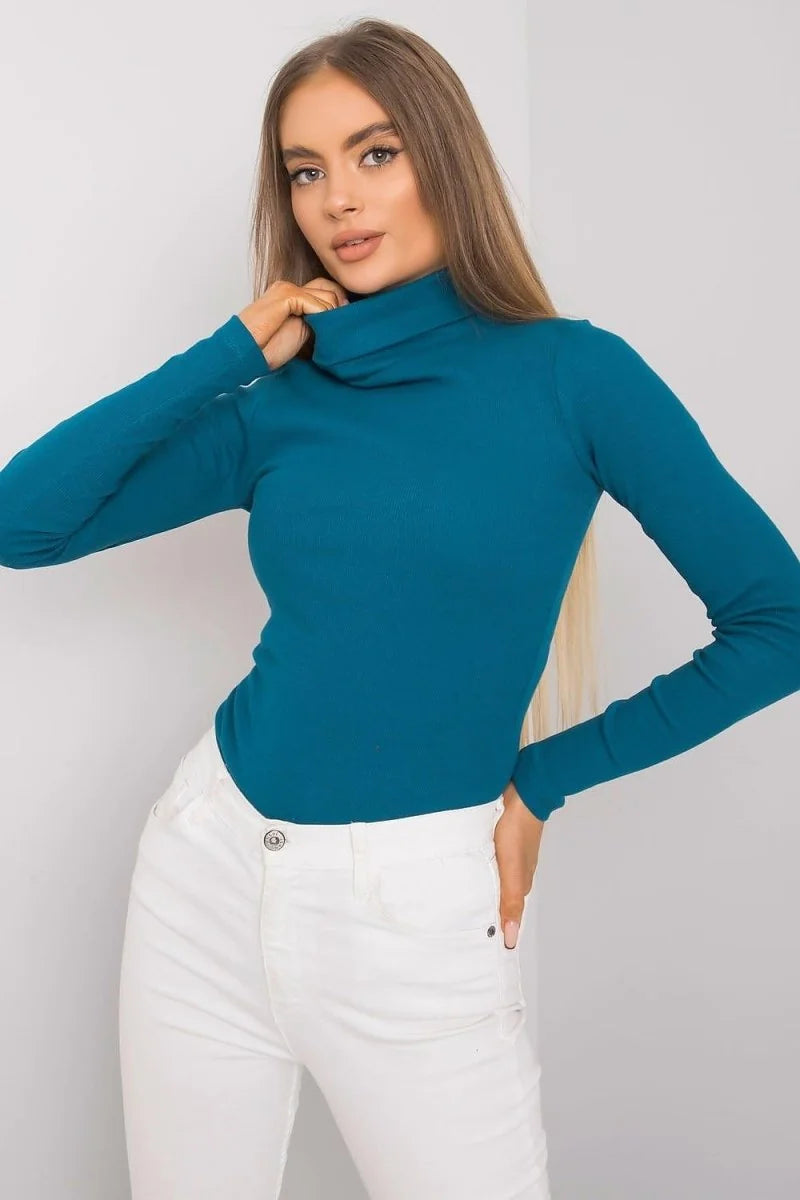 Fitted teal turtleneck top with long sleeves, paired with white jeans.