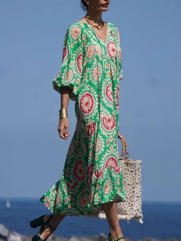 Green patterned maxi dress with v-neck and balloon sleeves, styled with a woven bag and heels.