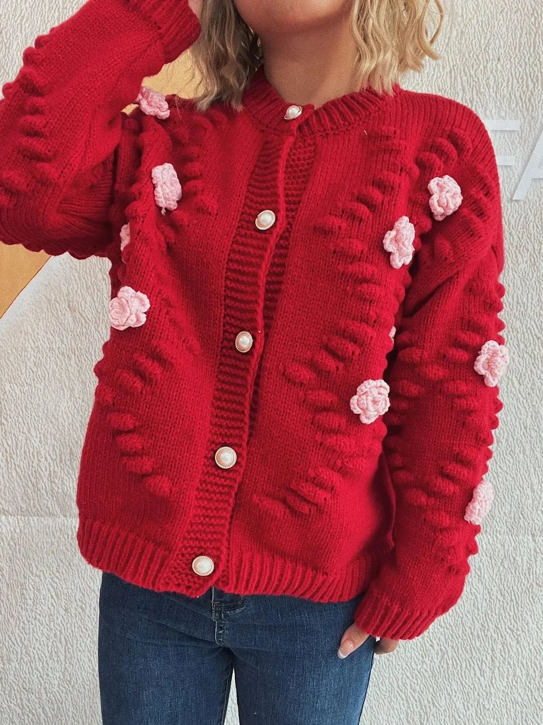 Red knit cardigan with floral appliques and pearl buttons.