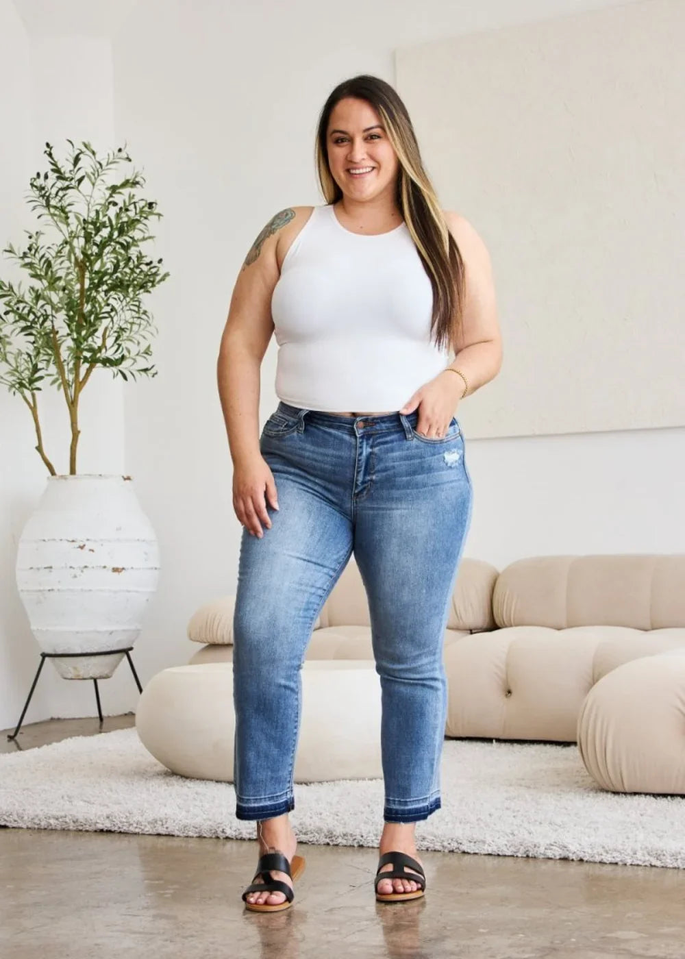 Medium wash denim jeans with frayed hem on a smiling model.