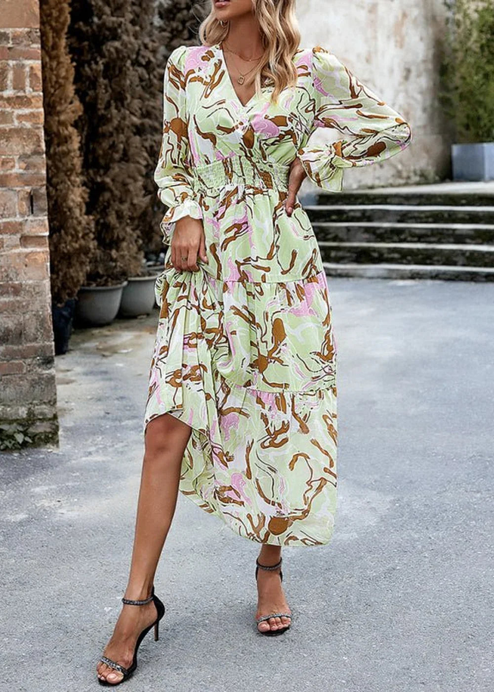 Light green maxi dress with a abstract print in brown and pink, featuring a cinched waist and tiered skirt.