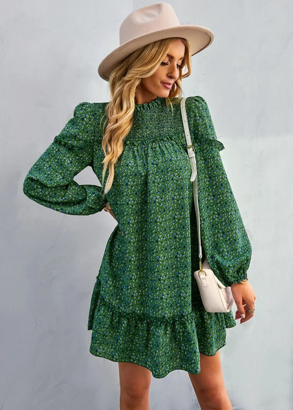 Green floral print dress with smocked bodice, puff sleeves, and tiered hem, worn with a cream crossbody bag.