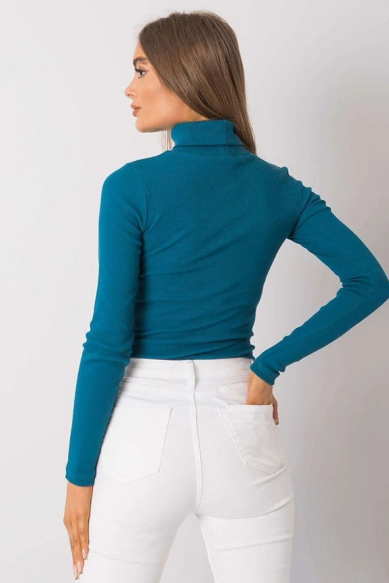 Teal ribbed turtleneck long-sleeve top with a fitted cut, shown from the back on a model wearing white jeans.