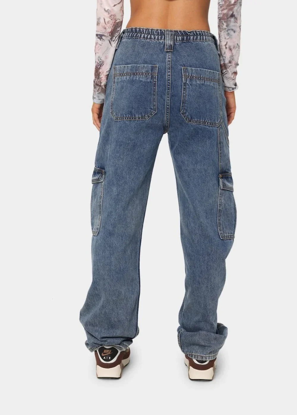 Back view of loose-fit denim cargo pants in a medium wash with visible stitching and large side pockets.