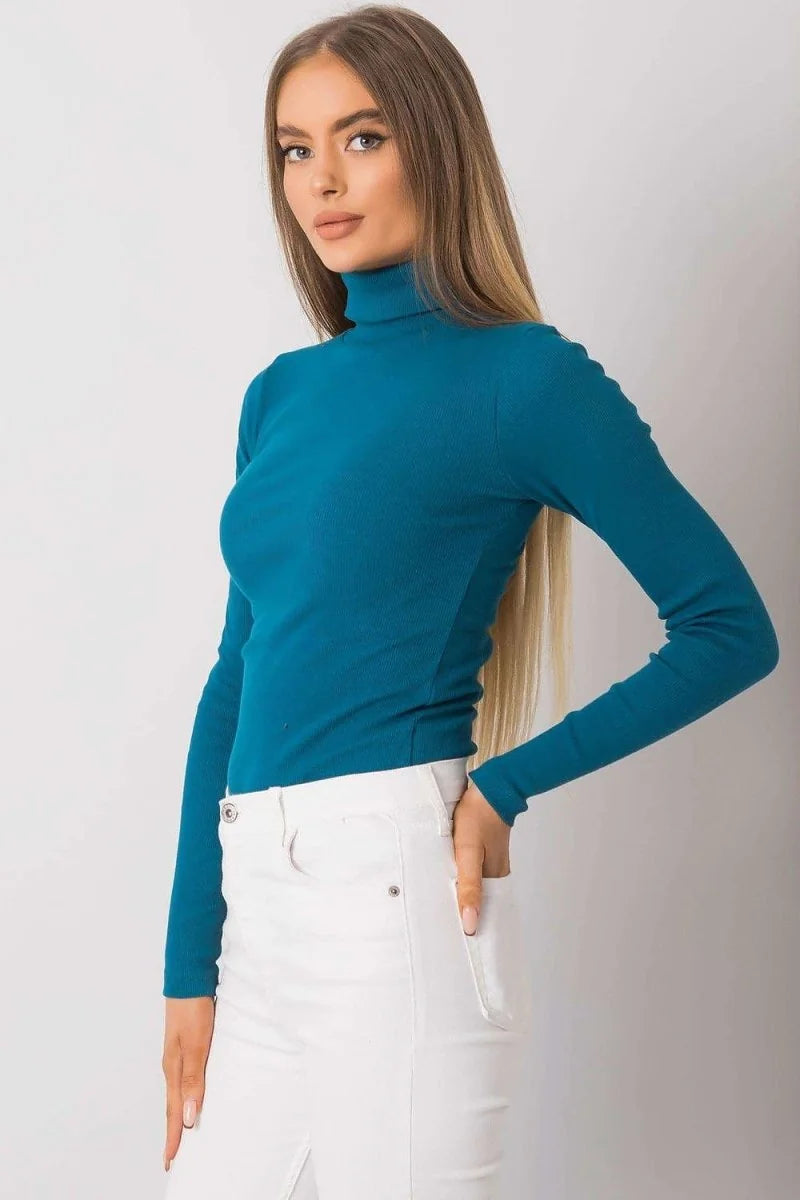 Fitted teal turtleneck top with long sleeves, worn by a model with white pants.