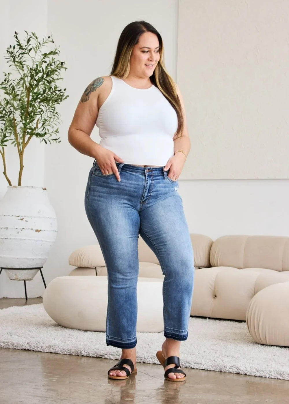 Medium wash flared jeans with frayed hem, on a model.