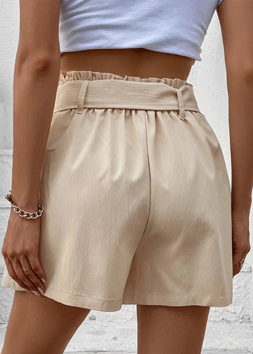 Back view of beige paperbag waist shorts with a matching belt and ruffled detail.