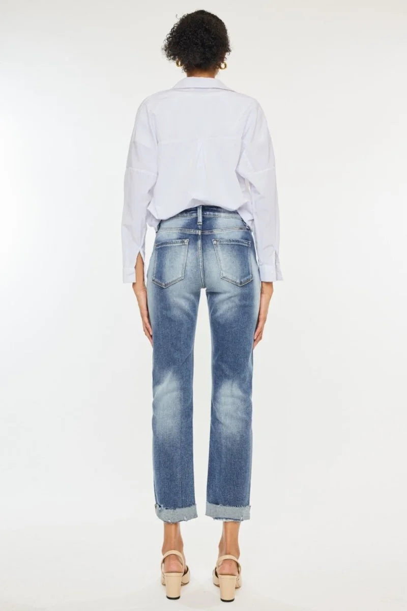 Distressed light wash denim jeans with cuffed hems, seen from the back on a model.